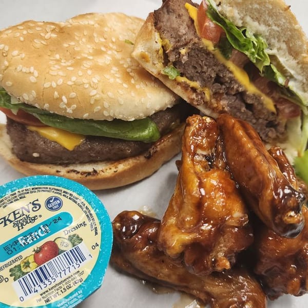 Cheeseburger with lettuce and tomato, a side of glazed chicken wings, and Ken's Steak House dressing.